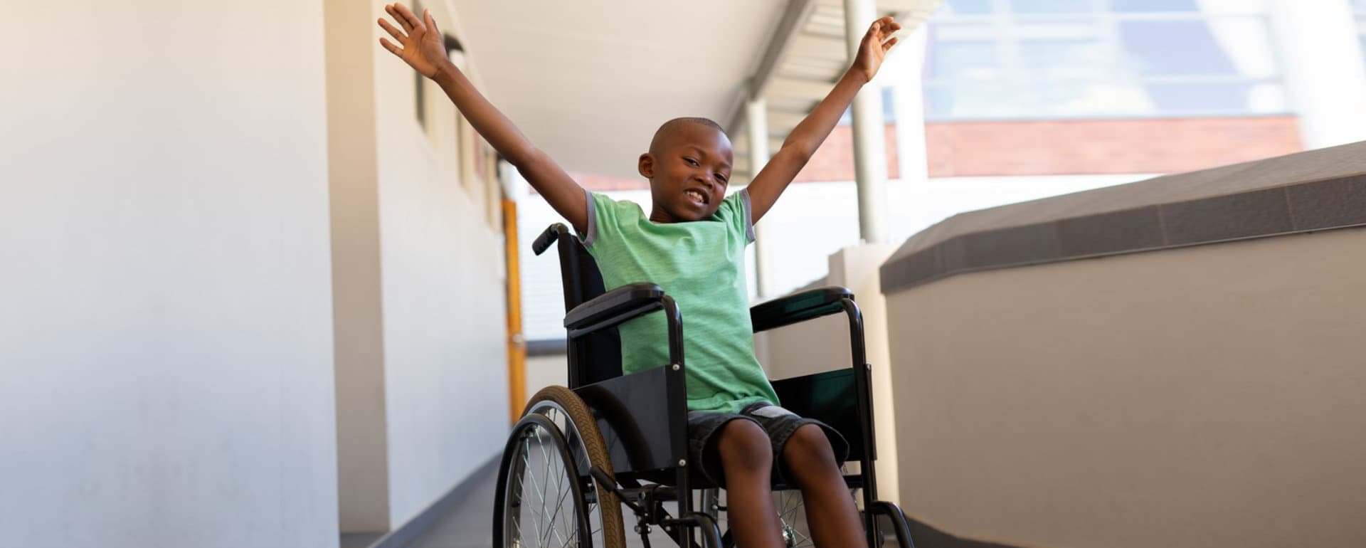 young disabled child raising his arms and smiling