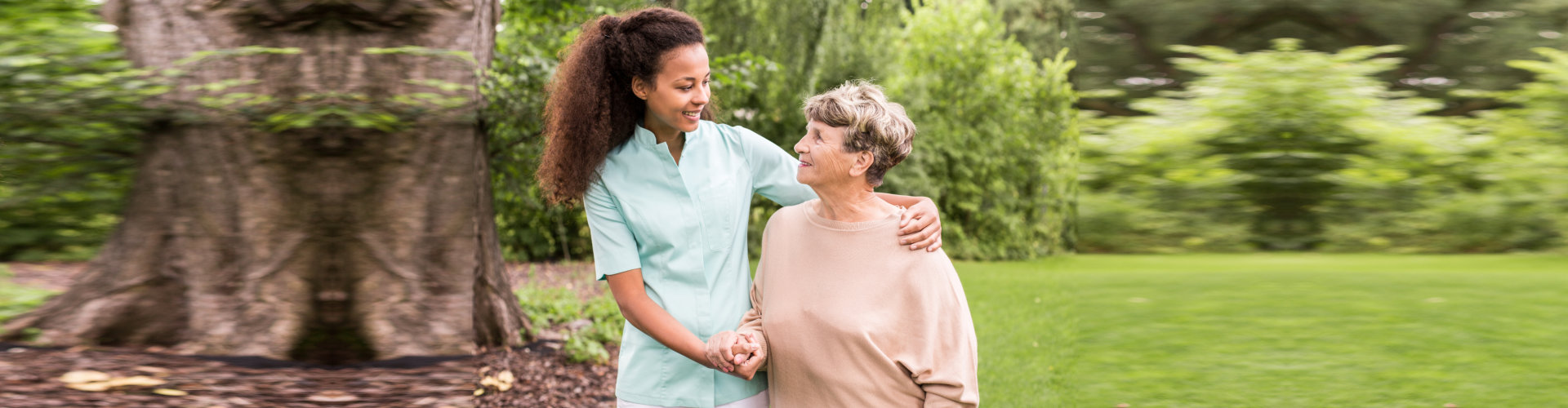 Caregiver and senior woman holding hands while smiling